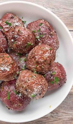 a white bowl filled with meatballs covered in parmesan sprinkles