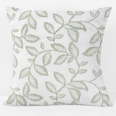 a white pillow with green leaves on it