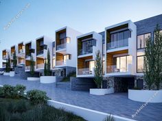 an artist's rendering of a row of modern apartment buildings at dusk, with trees and bushes in the foreground