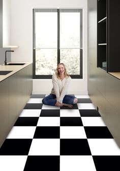 a woman sitting on the floor in a kitchen