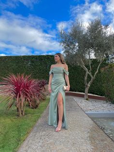 a woman in a green dress is standing outside