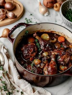 a pot filled with meat and vegetables on top of a white counter next to other dishes