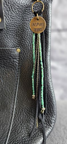 the inside of a purse with some beads hanging from it's handle and a tag that says inspire