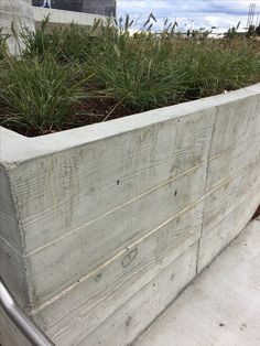 a concrete planter filled with lots of green plants