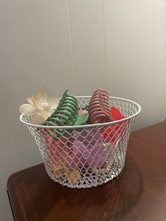 a wire basket filled with assorted cookies on top of a wooden table next to a white wall