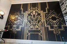 a black and gold art deco wall in a room with two lamps on either side