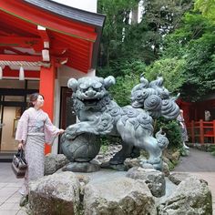 a woman standing next to a statue of a dog on rocks in front of a building