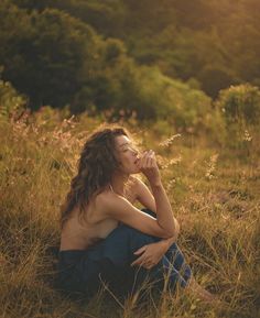 a shirtless man sitting on the ground in tall grass