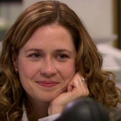 a woman sitting at a desk with her hand on her chin and looking off to the side