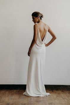 a woman in a white dress standing on a wooden floor with her back to the camera