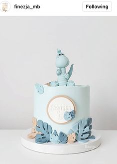 a blue and white cake with an animal topper sitting on it's side