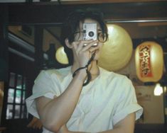 a man holding a camera up to his face while taking a selfie in front of him