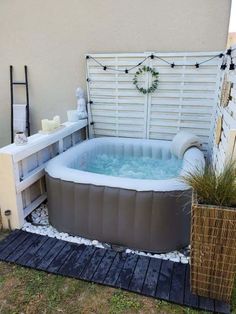 an inflatable hot tub sits outside on the lawn next to a potted plant