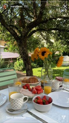 the table is set with breakfast food and fruit for two people to enjoy in the sun