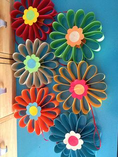 colorful paper flowers are hanging on the wall