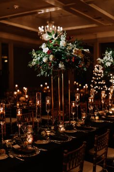 an elegant table setting with candles and flowers in tall vases on the centerpiece