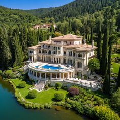 an aerial view of a large mansion with a pool in the middle and trees surrounding it