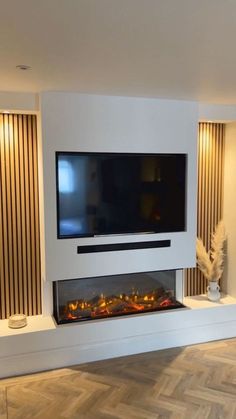 a living room with a large flat screen tv mounted on the wall next to a fireplace