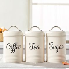 three white canisters with black lettering on them