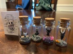 small glass bottles filled with tiny items sitting on top of a wooden table next to a card