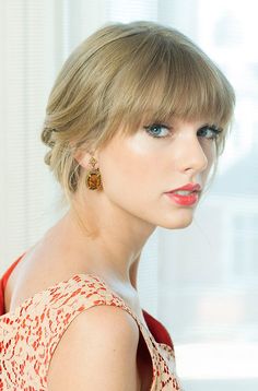 a close up of a person wearing a dress and earring with a curtain in the background