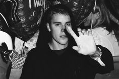 black and white photograph of a young man making the v sign with his fingers in front of him