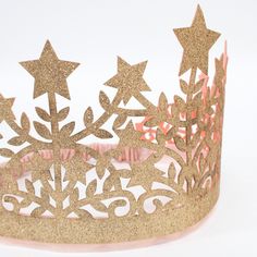 a tiara with gold glitter stars and scrolls on it's sides, against a white background