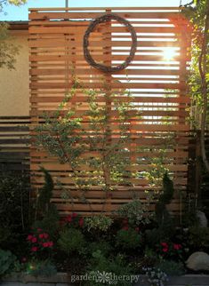 a wooden fence with a circular metal object on it's side in the middle of a garden