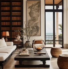 a living room filled with furniture and bookshelves next to a large open window