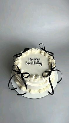 a birthday cake with the words happy birthday written on it and black ribbon around top