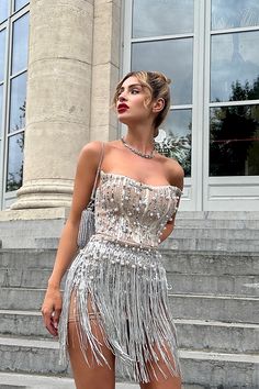 a woman in a silver dress standing on steps