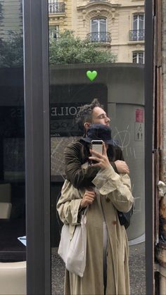 a man taking a selfie in front of a store window with his cell phone