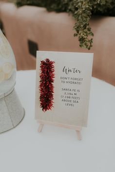 a sign that is sitting on top of a table next to a vase filled with flowers