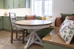 a kitchen with green cabinets and a table in the center surrounded by wooden bench seating