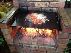 a brick oven with food cooking on it's side and flames in the middle