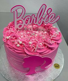 a birthday cake with pink frosting and decorations on the top is decorated with letters that spell out barbie