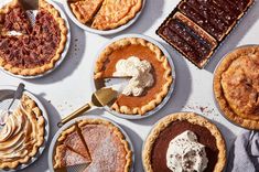 several pies are arranged on a table with spoons