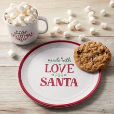 a plate with a cookie and marshmallows on it next to a cup of coffee