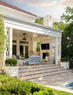 an outdoor patio with chairs and steps leading up to the front door, next to a swimming pool