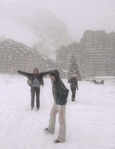 three people are standing in the snow with their arms out and one person is pointing