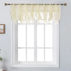 a white window with sheer curtains in front of it and a potted plant next to the window