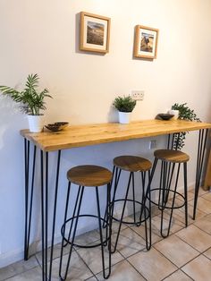 three wooden stools sitting under a table with plants on it