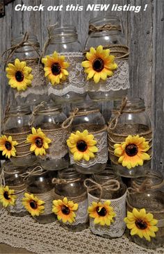 mason jars with sunflowers tied to them are sitting on a doily in front of a wooden wall