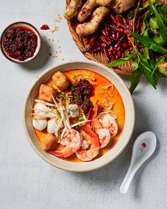 a bowl of soup with shrimp, croutons and other vegetables next to it