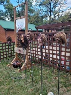 several fake heads are placed on top of wooden poles in front of a yard fence