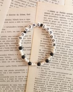 a bracelet with black and white beads on top of an open book that says london