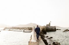 the bride and groom are walking along the pier