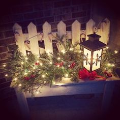 a lantern is sitting on top of a table with christmas garland and lights around it