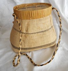 an old woven basket with rope around it on a white sheet covered bedding area