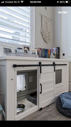 a white dog house with a cat bed in it's center and window behind it